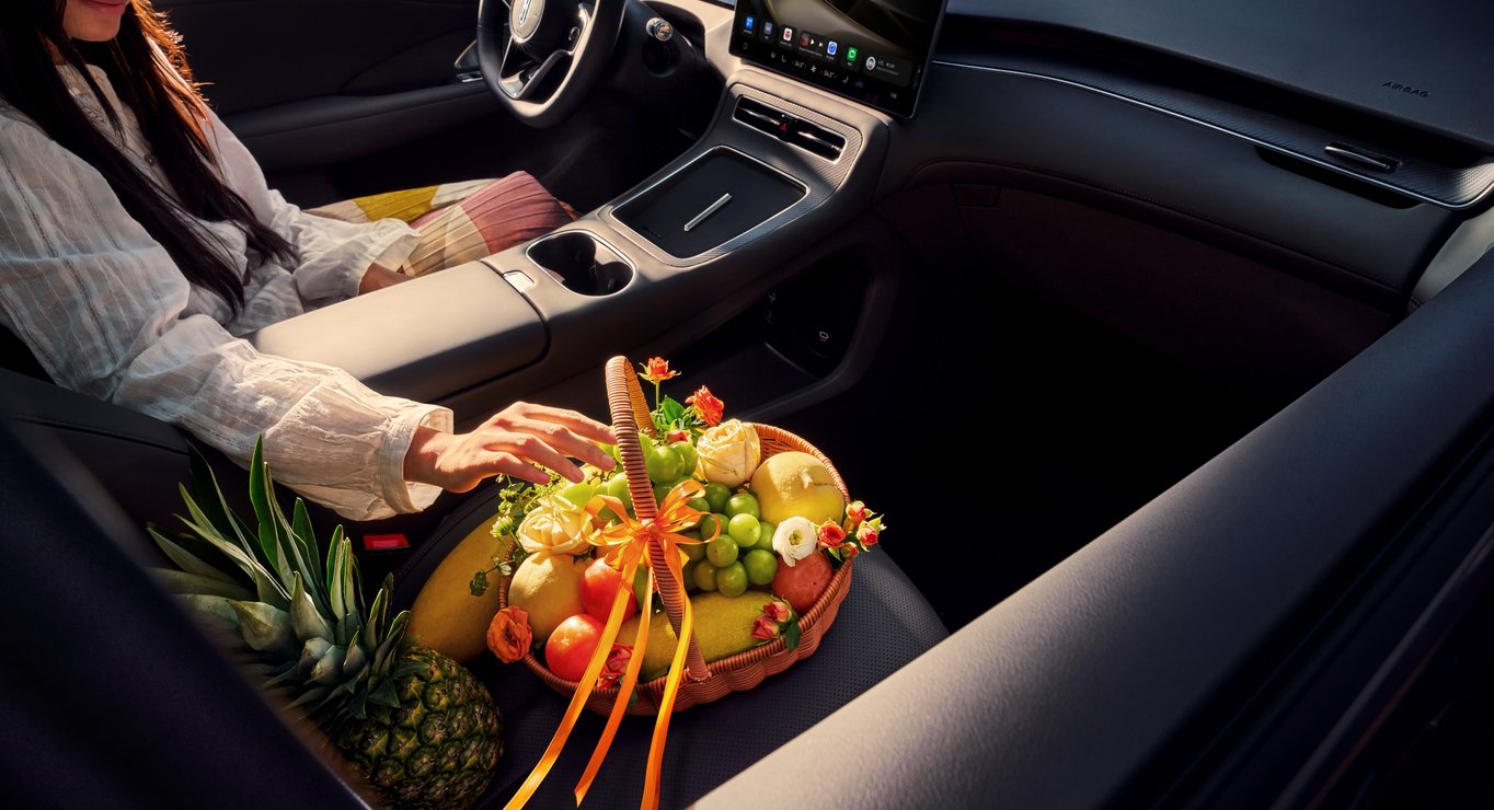 一名女性坐在主驾，旁边是新鲜水果，展示了健康座舱