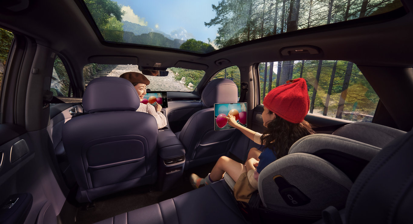 两个人分别坐在前排和后排，同时共享屏幕，展示了华为 maglink 双屏互联功能