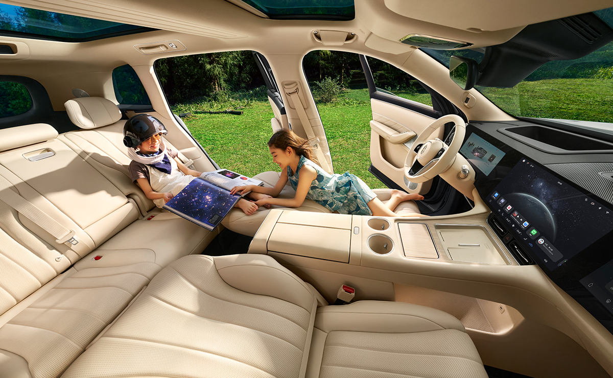 一家三口一起坐在问界 M8 白沙杏主副驾折叠后的二排座位上