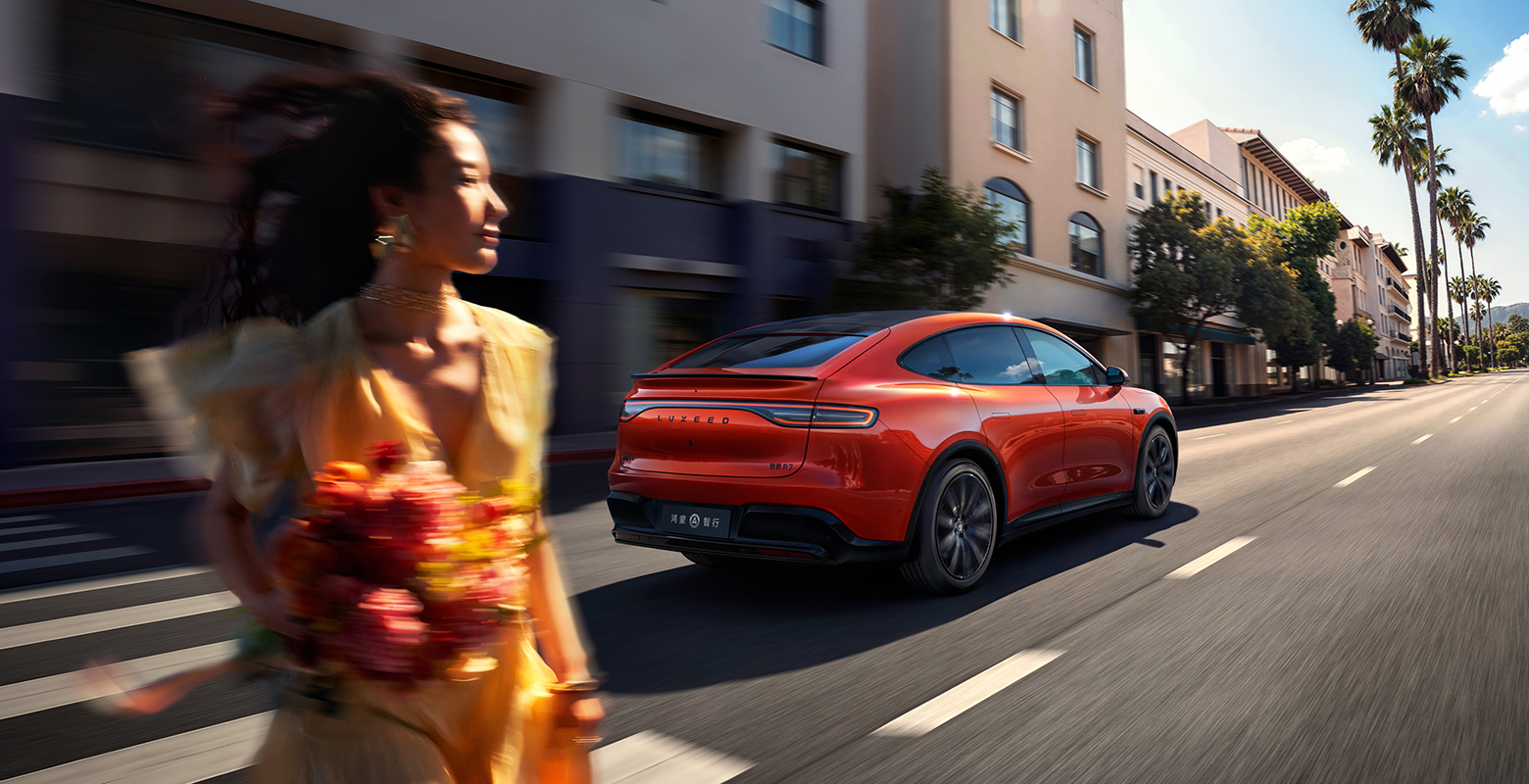 智界 R7 活力橙增程版行驶在路面，展示其长续航性能
