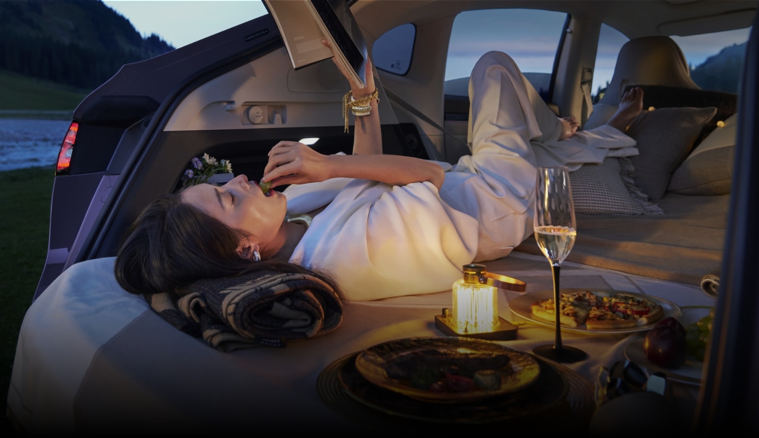 一位女士自由地躺在后排享受阅读时光，展示了智界 R7 后排座椅放平变床车的多元功能