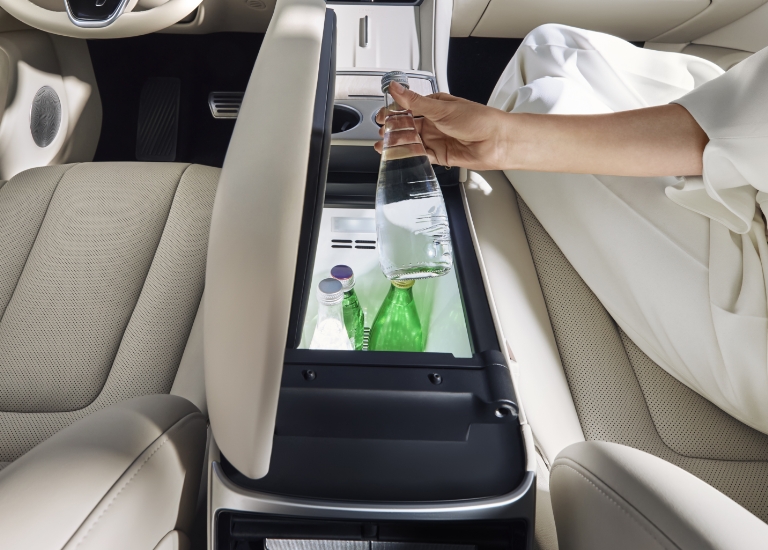 女士从副驾驶位打开冷暖箱，拿出一瓶饮料，展示了智界 R7 的车载冷暖箱功能